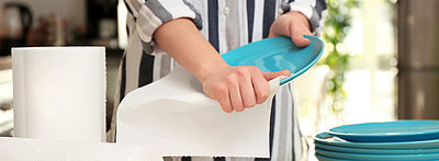 Abbildung von einer Frau, die Teller mit Papiertüchern abwischt